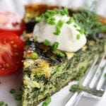 Piece of Crustless Spinach Quiche garnished with chives and sour cream.