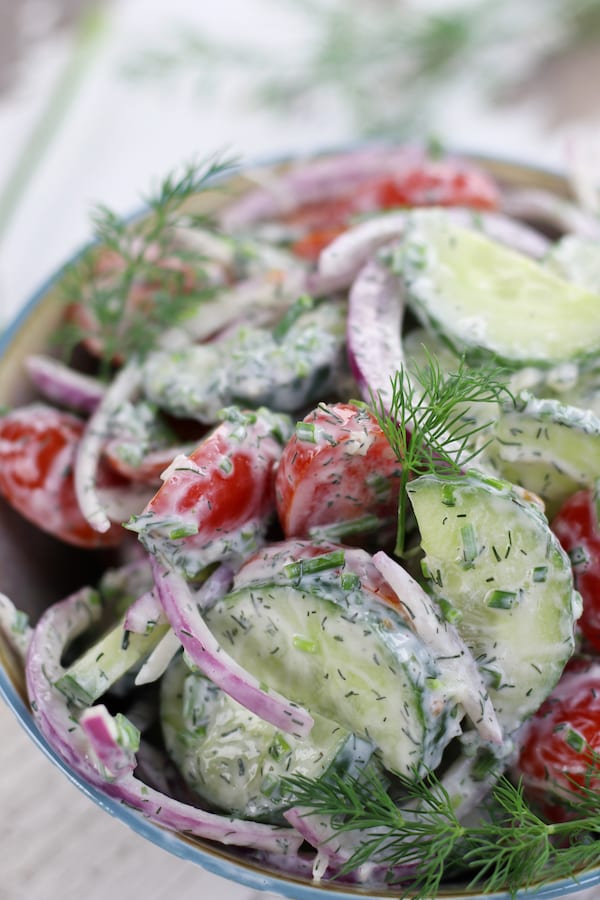 A bowl of Cucumber Dill Salad on a white table.