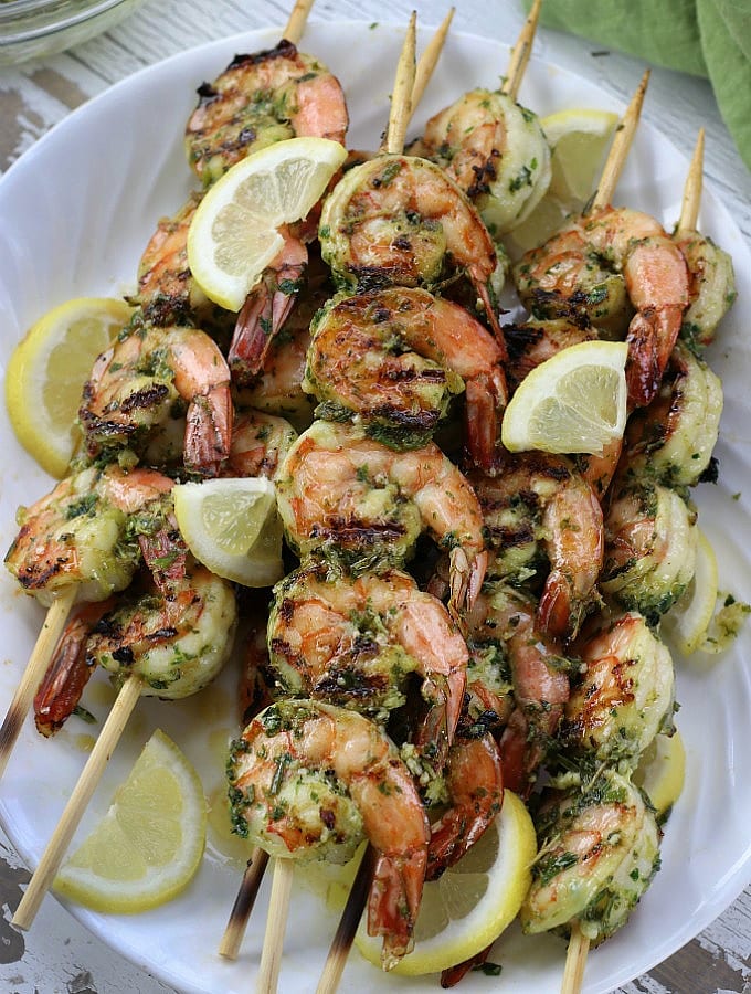 Marinated Grilled Shrimp Kabobs on a white plate with lemon wedges.