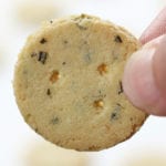 Up close shot of two fingers holding a Rosemary Parmesan Almond Crackers.