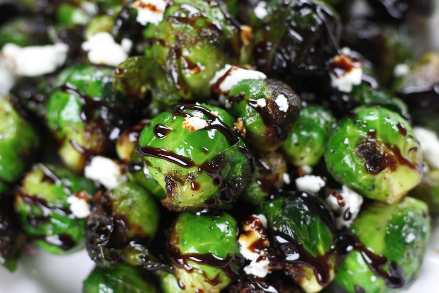Balsamic Brussel Sprouts sprinkled with feta on a white plate.