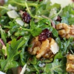 Up close photo of Arugula Pear Salad with whole candied walnuts and cranberries.