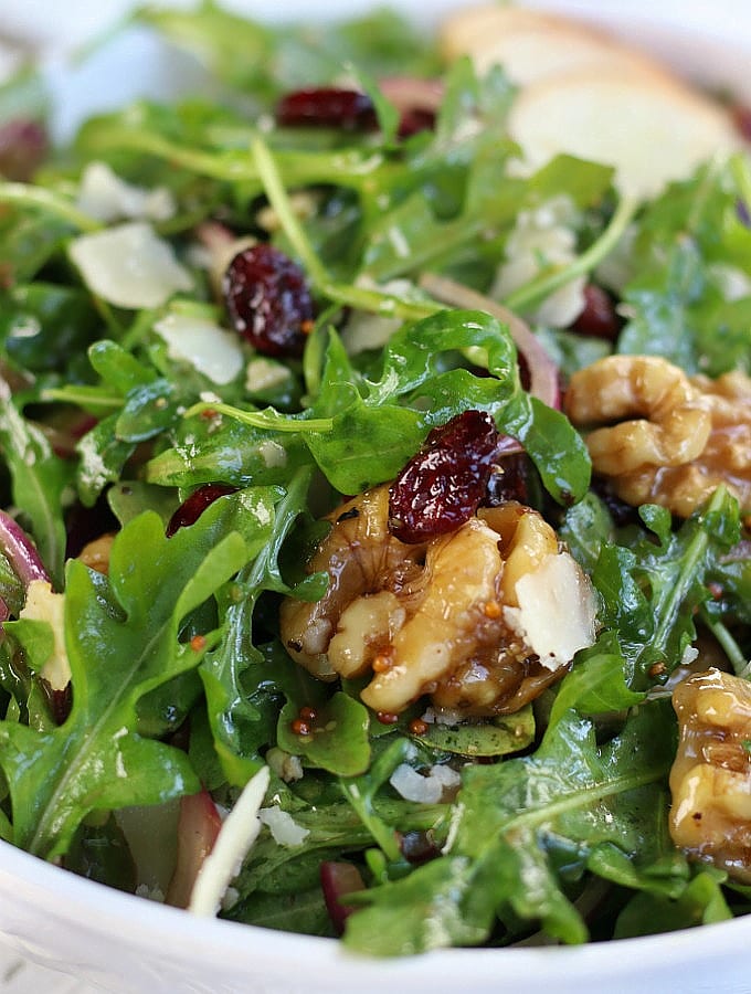 Up close photo of Arugula Pear Salad with whole candied walnuts and cranberries.