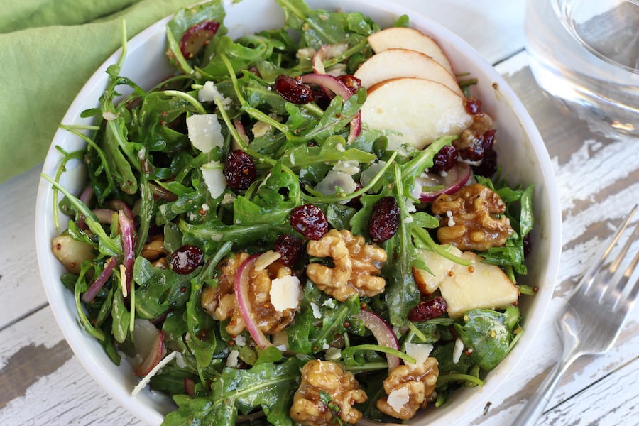 Rocket Pear and Walnut Salad in white bowl on a white table.