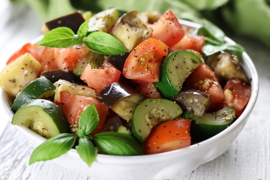 Vegan Ratatouille in a white bowl on a white wooden table.