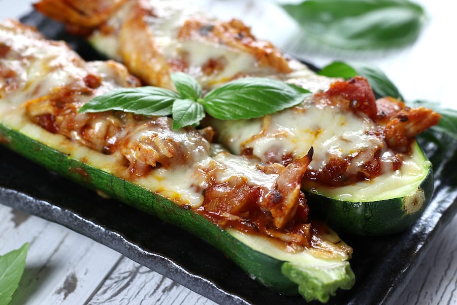 Chicken and Zucchini Boats on a grey plate garnished with basil.