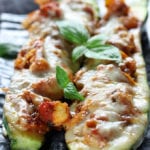 Two Italian Chicken Zucchini Boats on a grey plate.