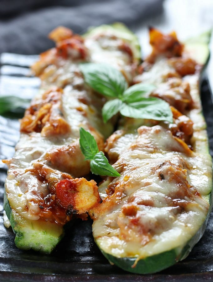 Two Italian Chicken Zucchini Boats on a grey plate.
