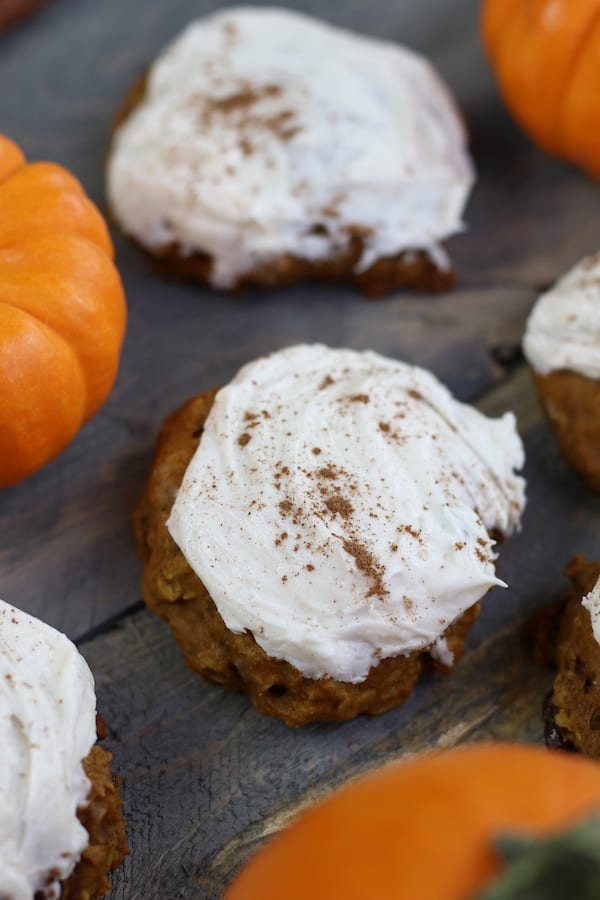 Old Fashioned Pumpkin Cookies sitting on a wooden table with small pumpkins.