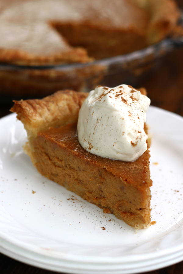 A slice of Pumpkin Pie From Scratch sitting on a white plate.