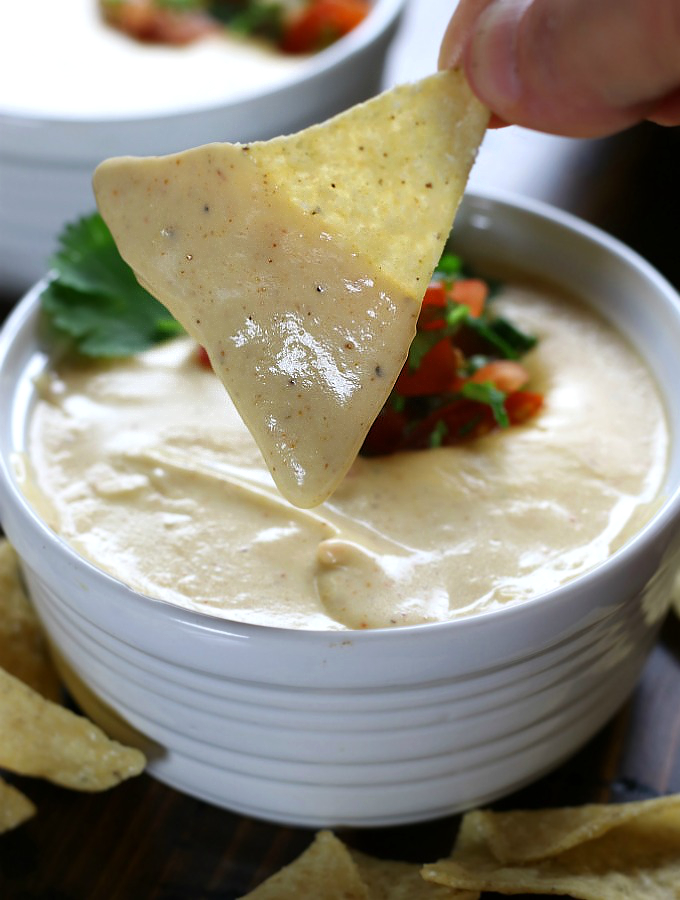 Chip dipping into Ultra Creamy Nacho Cheese.