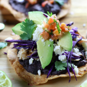 Baked Tostadas with refried black beans, shredded chicken and avocado slices.