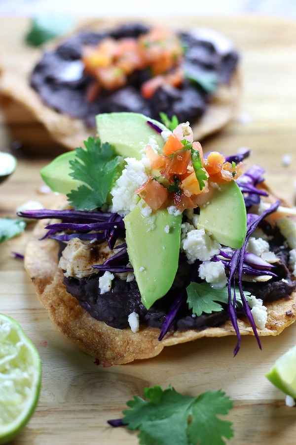 Baked Tostadas with refried black beans, shredded chicken and avocado slices.