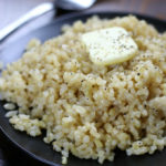 Cooked Short Grain Brown Rice on a plate with butter and pepper.