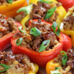 Yellow, orange and red Asian Stuffed Peppers garnished with green onions.