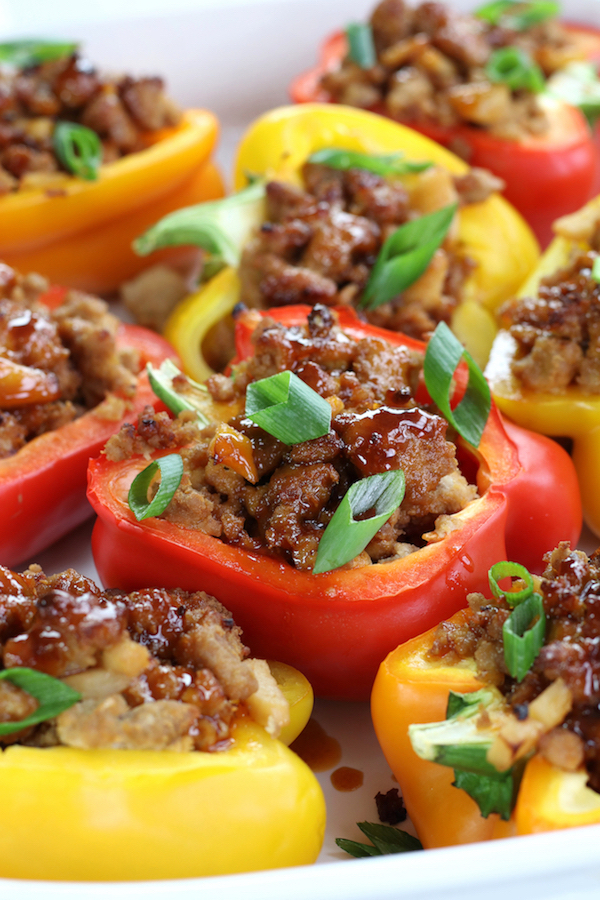 Yellow, orange and red Asian Stuffed Peppers garnished with green onions.