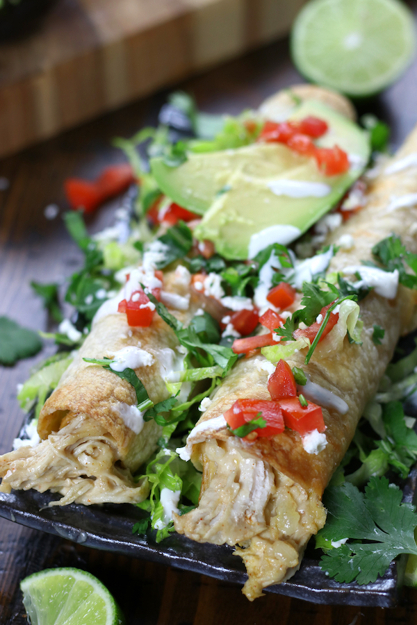 Flautas with shredded chicken on a grey plate.