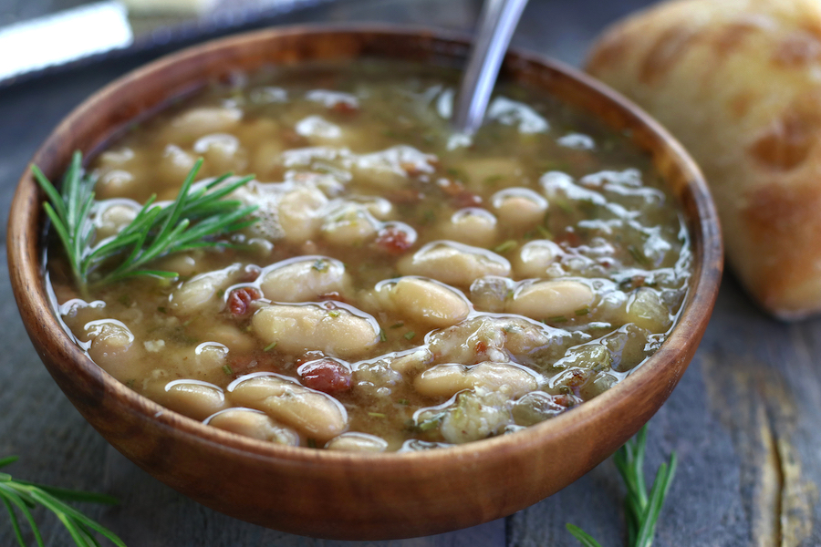 Italian Bean Soup in a bowl with fresh sprigs of rosemary.