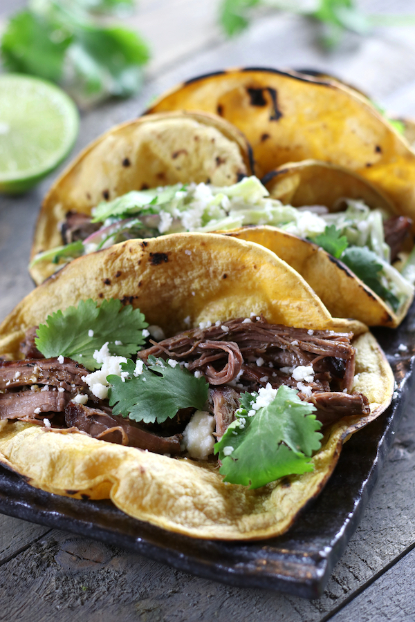 Slow Cooker Tacos garnished with Queso Fresco and fresh cilantro.