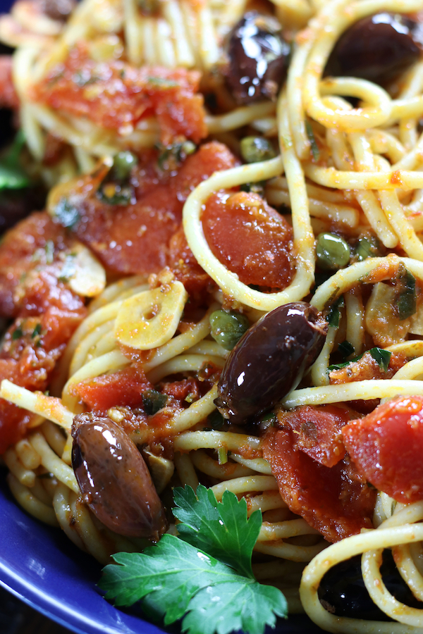 Spaghetti Puttanesca with whole olives, capers and garlic slices.