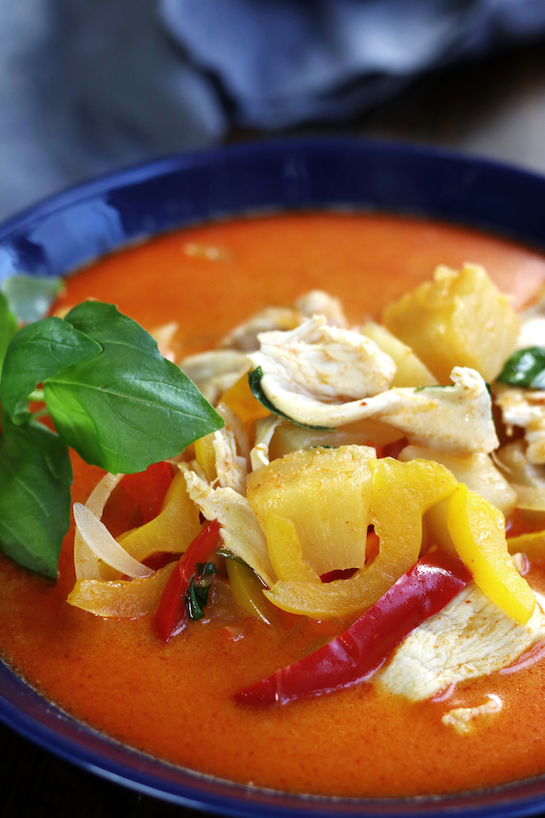 Chicken Curry Recipe with pineapple and basil in a blue bowl.