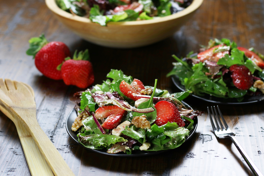 Two plates of Spring Mix Salad Recipe on a brown table.