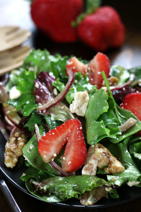 Strawberry Salad on a black plate with feta, walnuts and red onion.