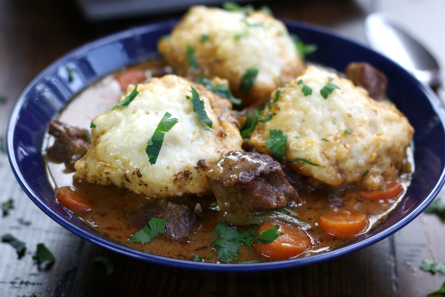 Blue bowl of Beef Stew and Dumplings with carrots and 3 dumplings.