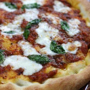 Pizza Napolentana with fresh basil leaves and mozzarella.