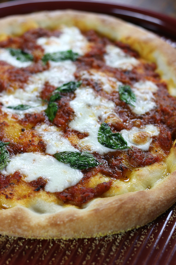 Pizza Napolentana with fresh basil leaves and mozzarella.