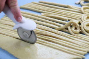 Cutting of Pici Dough into Strips using a pizza cutter.