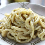 Creamy Pici Cacio e Pepe on a patterned plate.