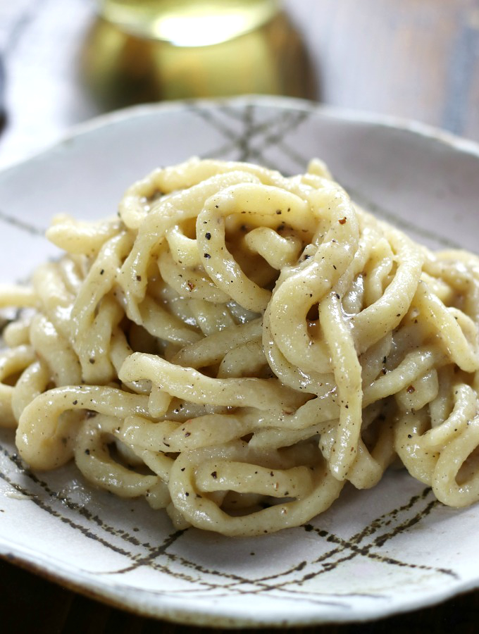 Creamy Pici Cacio e Pepe on a patterned plate.