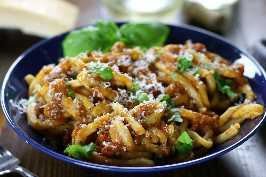 Sugo Aglione (Tomato-Gralic Sauce) covers hand rolled pasta with fresh torn basil and grated parmesan cheese.