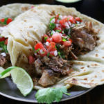 Carnitas meat in two flour tortillas with fresh salsa.