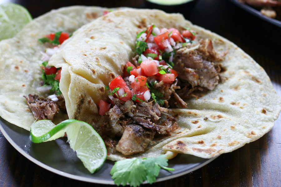 Carnitas meat in two flour tortillas with fresh salsa.