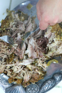 Shredding Cooked Pork Carnitas on a silver platter.