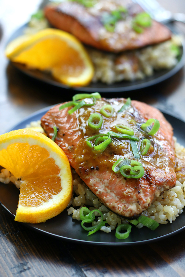 Two plates of Orange Glazed Salmon ditto on a wooden surface.