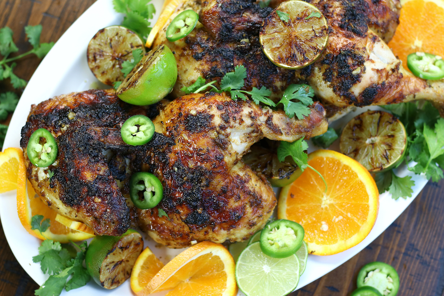 Overnight Marinated Chicken that has been roasted and garnished with limes and orange slices.