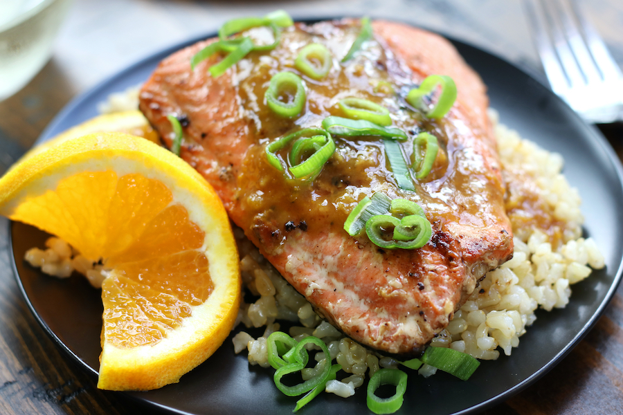 Seared Salmon with Skin on a plate with an orange slice that is curled.