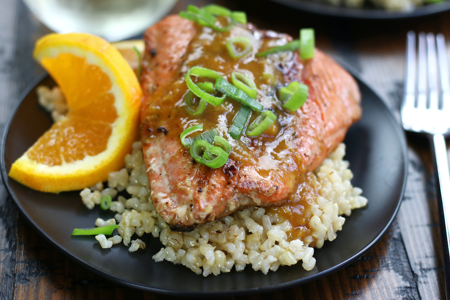 Seared and Glazed Salmon garnished with green onions and an orange slice.