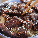 Chopsticks picking up a piece of beef from Asian Beef Strips Recipe.