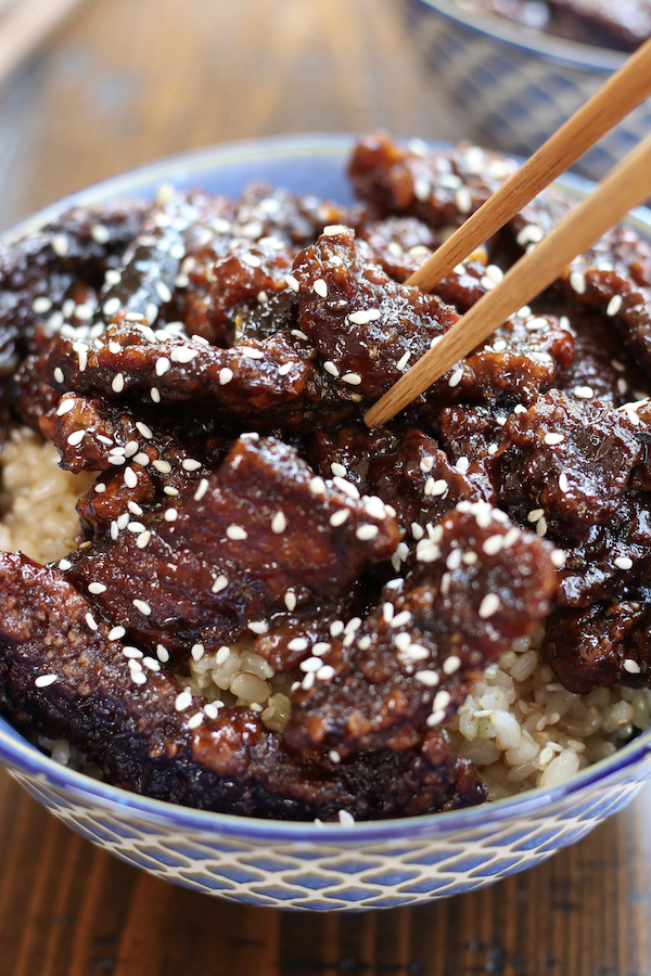 Chopsticks picking up a piece of beef from Asian Beef Strips Recipe.