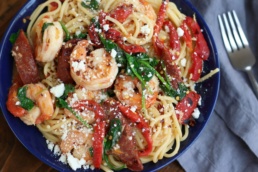 Overhead photo of Prawn Chorizo Pasta in a bowl sitting next to a grey napkin and a fork.