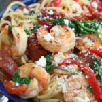 Prawn and Chorizo Pasta in a blue bowl garnished with crumbled cheese.