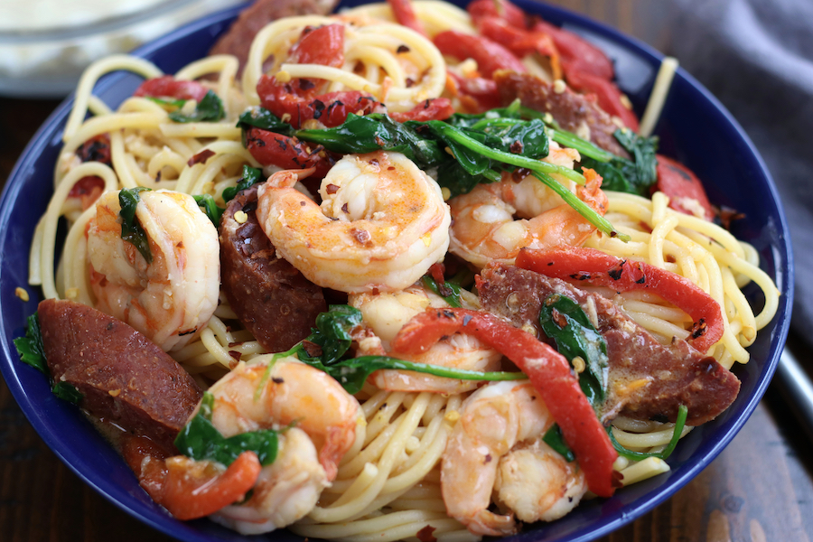 A bowl of Shrimp and Chorizo Pasta in a blue bowl sitting on a wooden table.