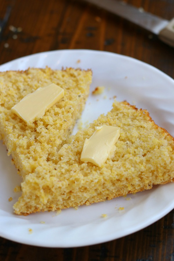 A slice of Easy Cornbread Recipe cut in half with dabs of butter.