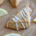 Lemon Scones sitting on brown parchment paper with a lemon glaze.