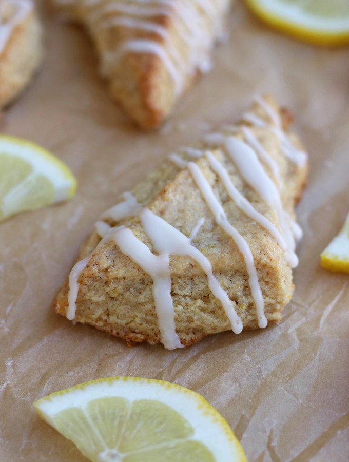 Lemon Scones sitting on brown parchment paper with a lemon glaze.