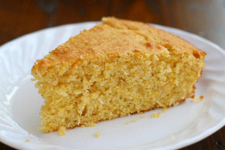 A slice of Simple Cornbread Recipe sitting on a white plate.